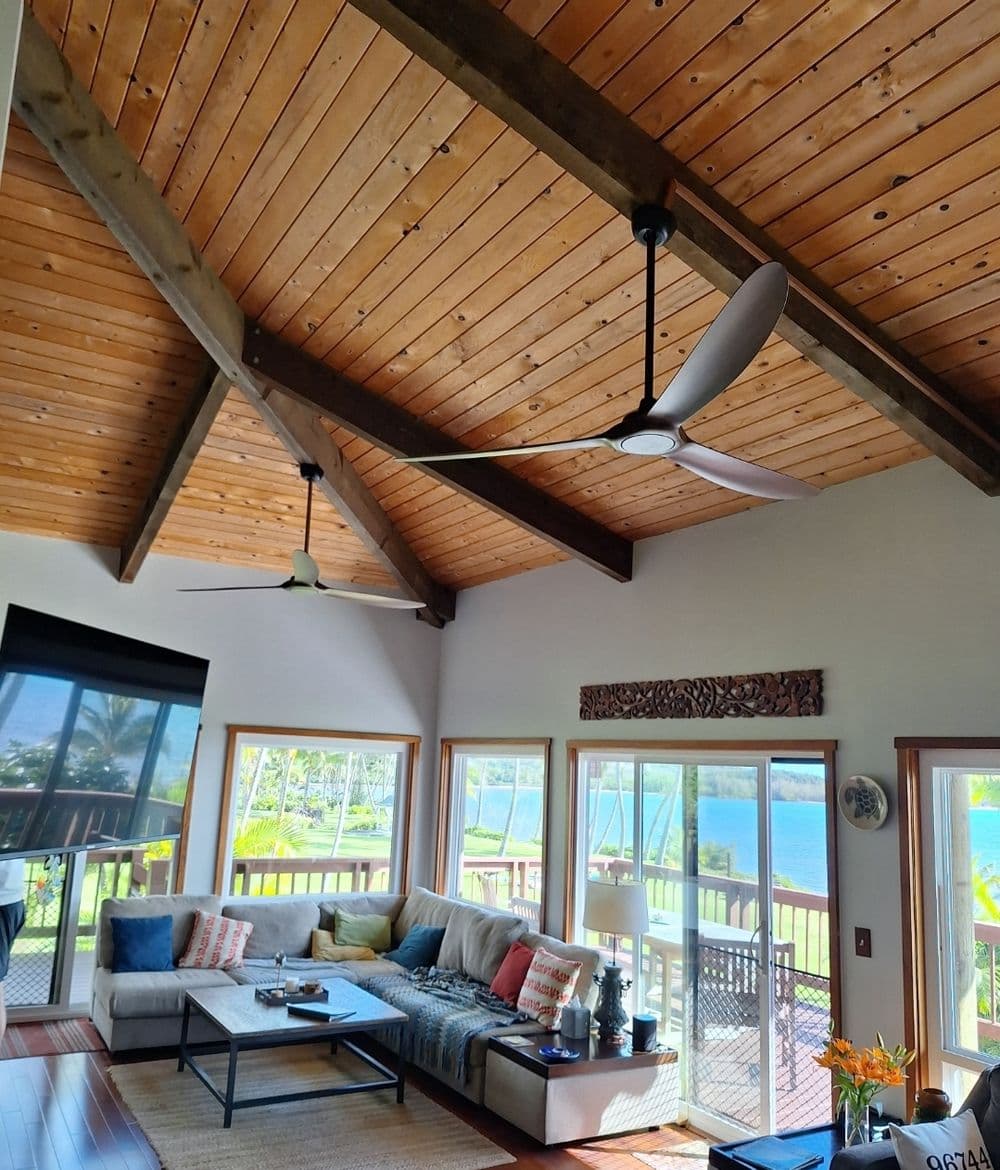 Bright living room with vaulted wood ceiling, modern furniture, and scenic ocean view.
