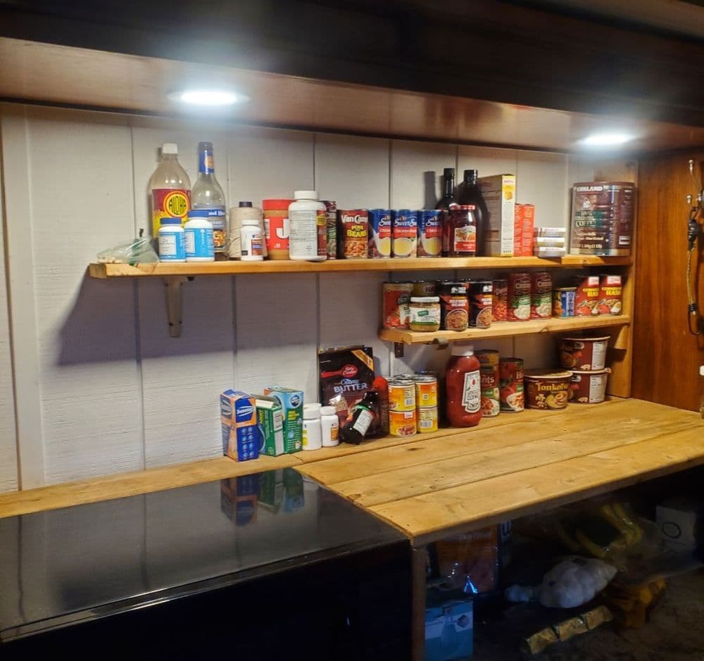 Organized kitchen shelf featuring various condiments, canned goods, and cooking supplies.