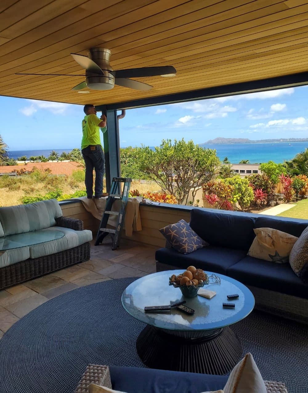 Worker adjusting window shades on a patio overlooking a beautiful ocean view.