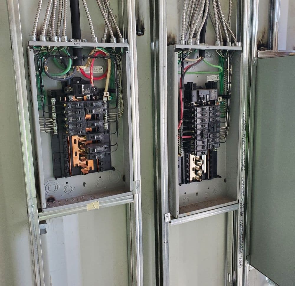 Electrical panel with circuit breakers and wiring, showing both sides of the setup.