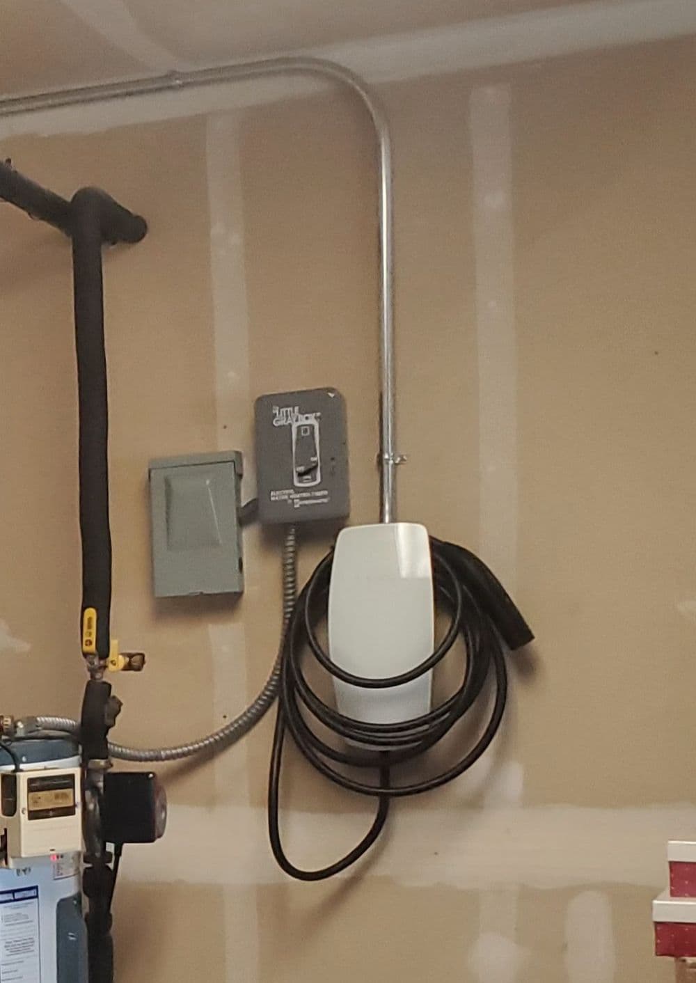 Wall-mounted electric equipment with cables in a garage setting.