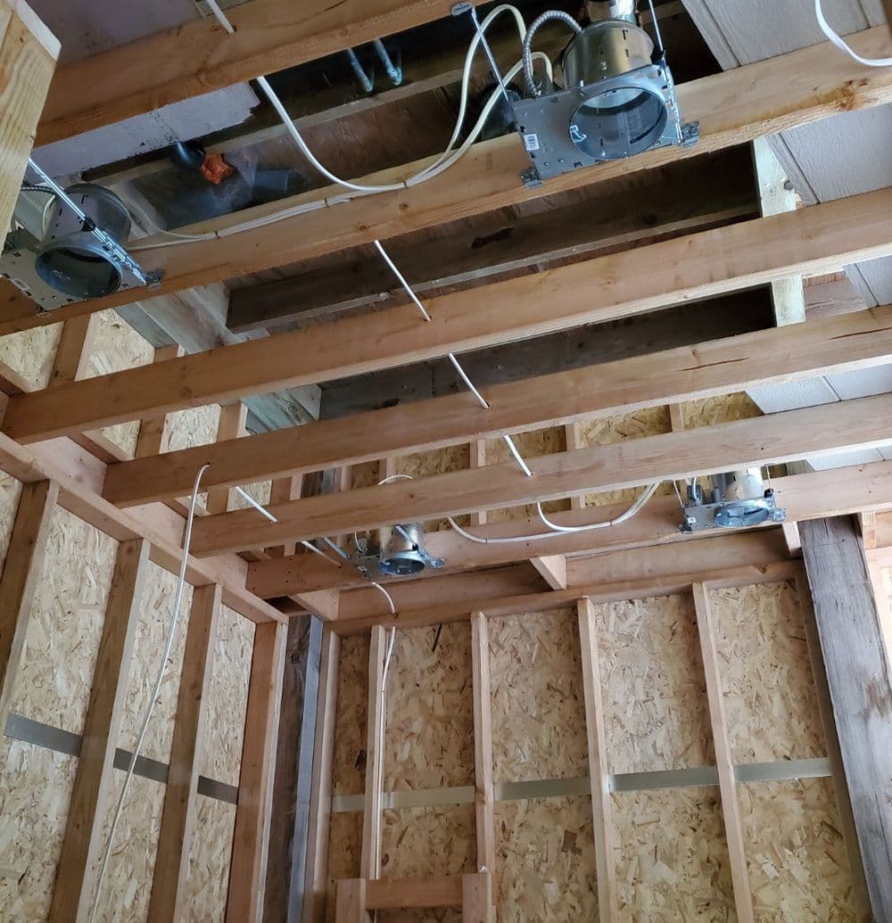 Exposed wooden beams with electrical fixtures during home renovation.