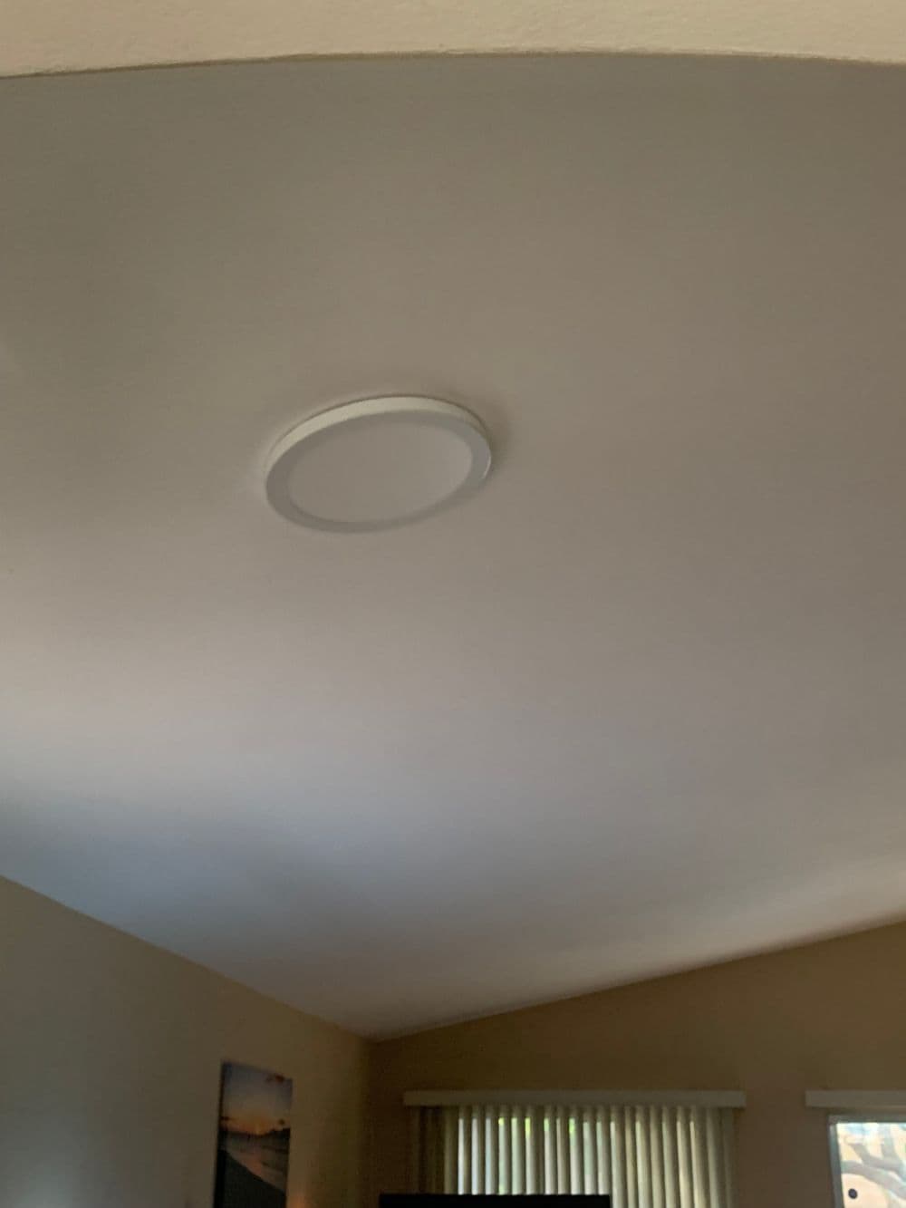 Ceiling with modern round light fixture in a warmly lit room.