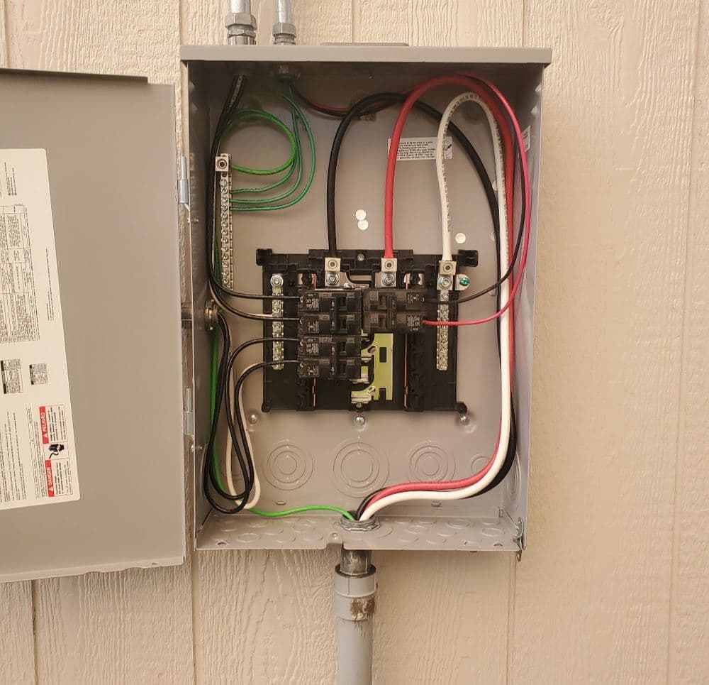 Image of an open electrical panel showing circuit breakers and wiring connections.
