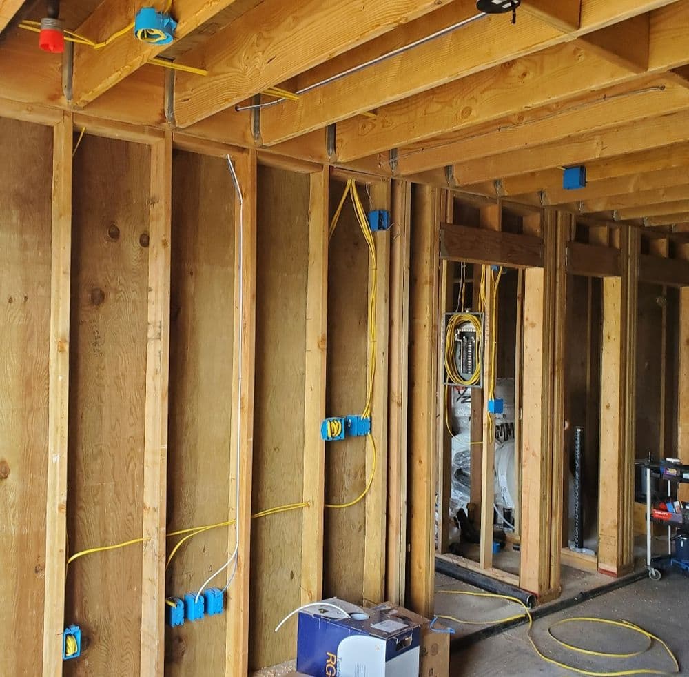 Interior view of a home under construction, showcasing exposed wooden framing and electrical wiring.