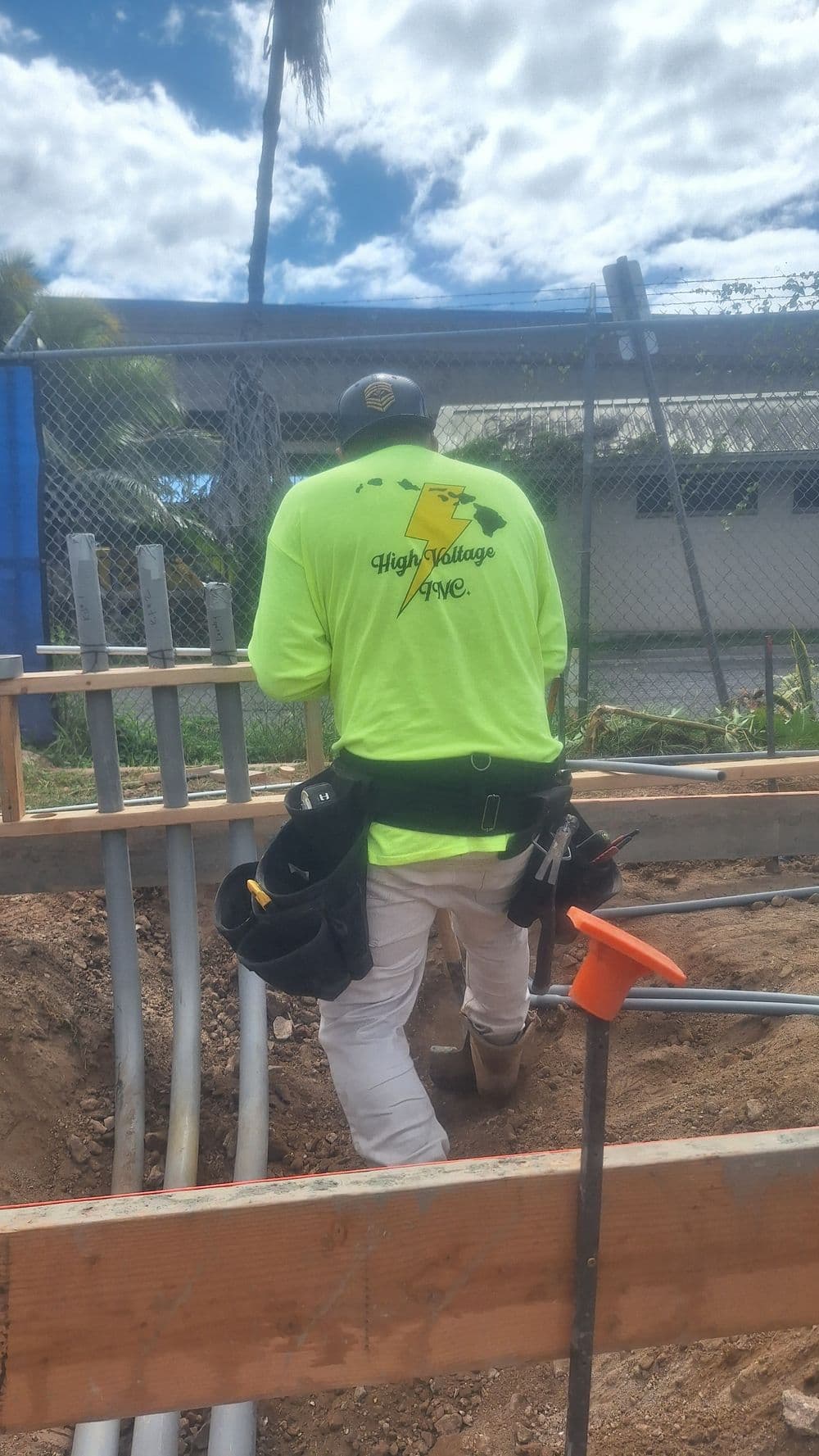 Worker in neon yellow shirt at construction site, preparing high-voltage wiring.