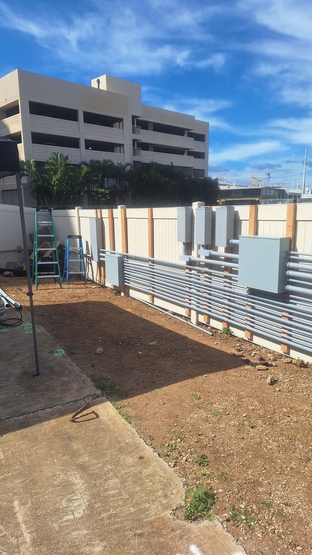 Construction site featuring electrical panels and conduit installation against a blue sky.