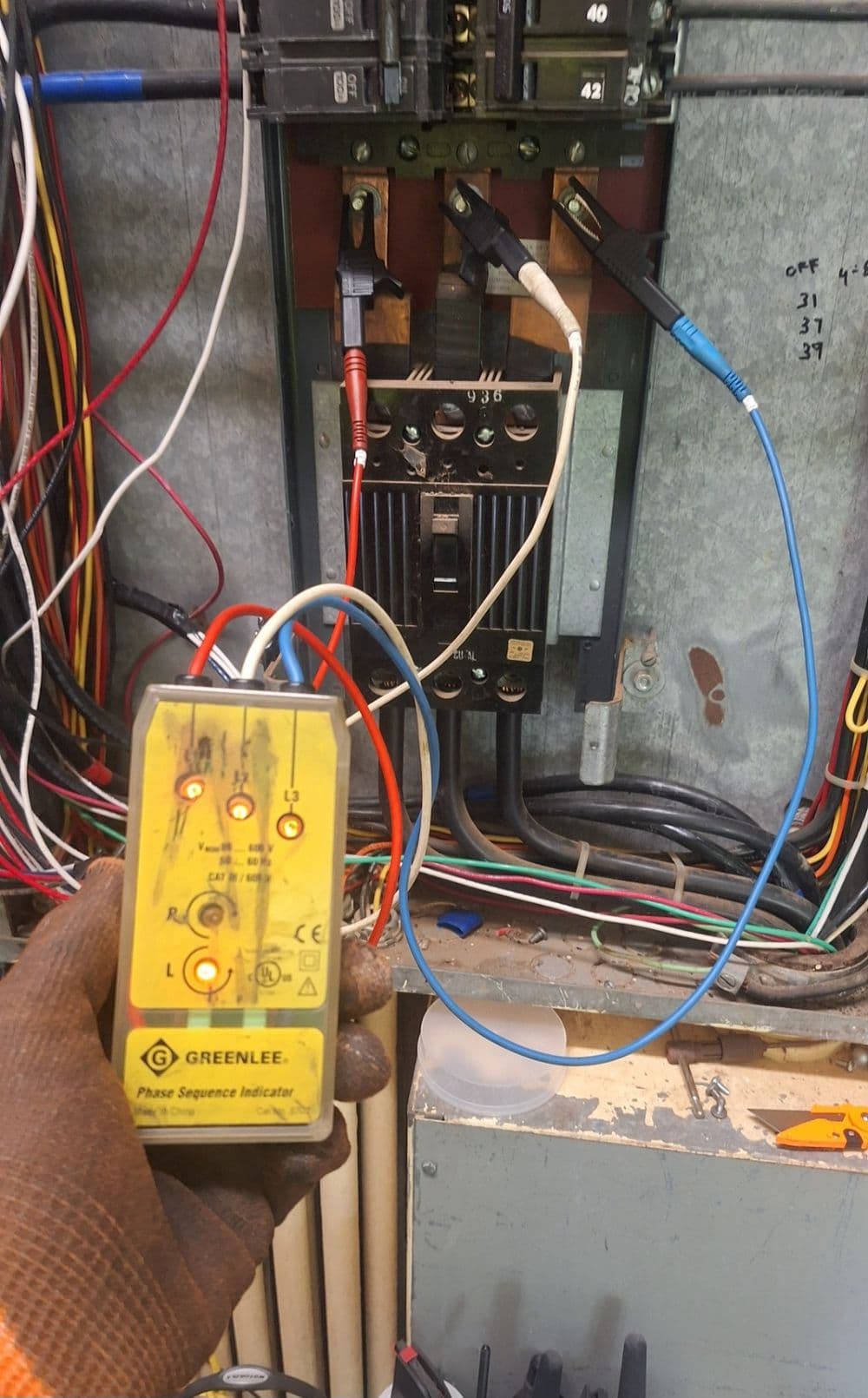 Phase sequence indicator testing electrical panel with multiple wires connected.