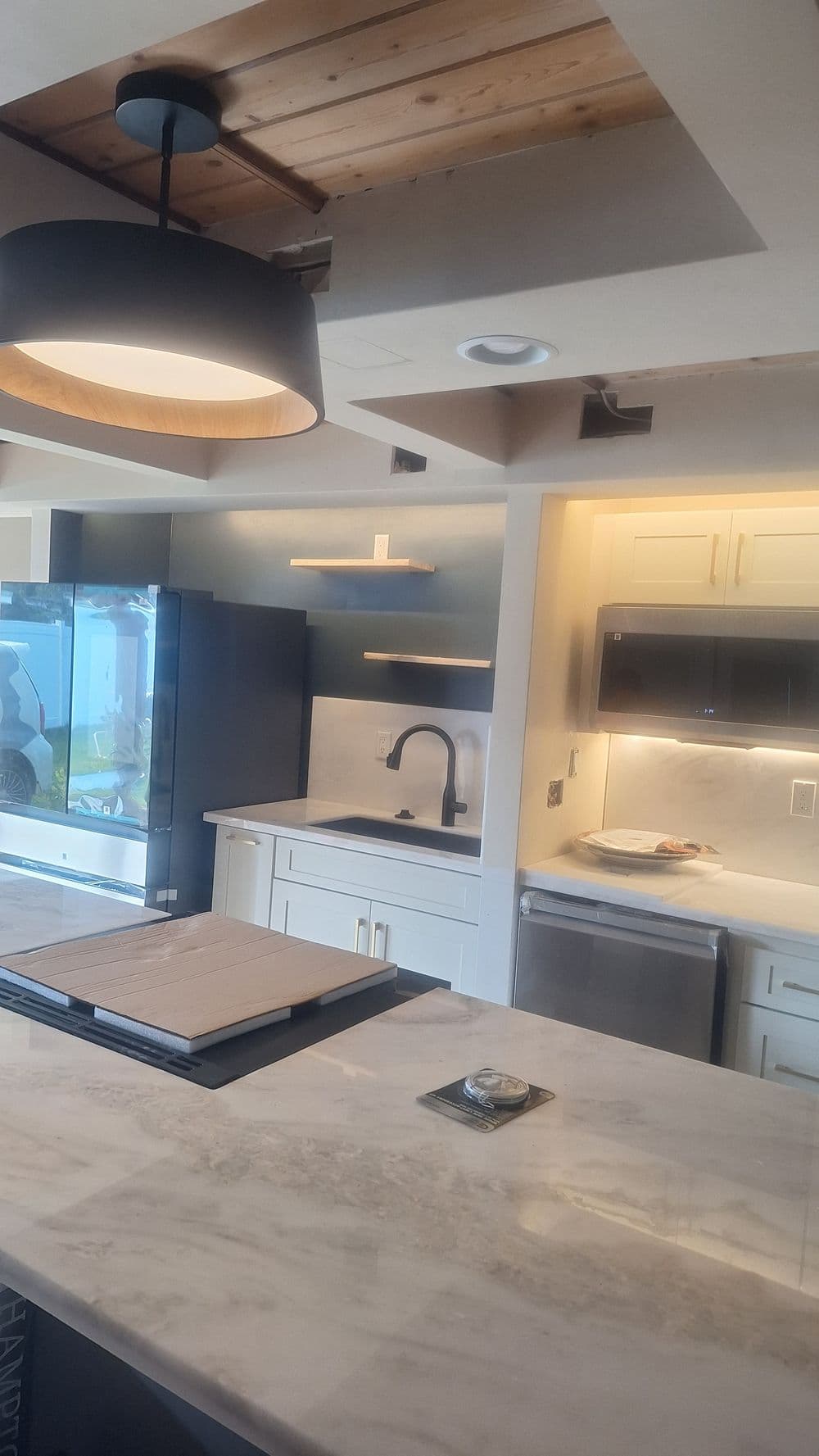 Modern kitchen with marble countertops, black fixtures, and stylish lighting.